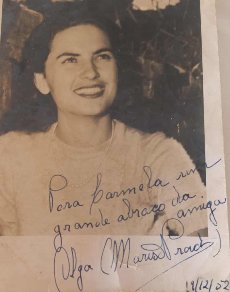 A foto é uma lembrança autografada para amigas e pertence ao acervo da família  de Carmela Pinotti dos Santos. Observem que atriz ainda  assina , conservando o nome " Olga"  acrescido do nome artístico "Marisa Prado", com data de  19/12/1952, prestes a completar 22 anos.